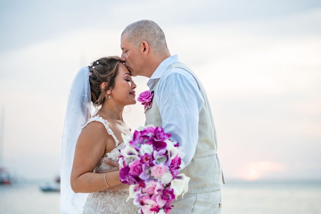 Groom kissing bride forehead at wedding
