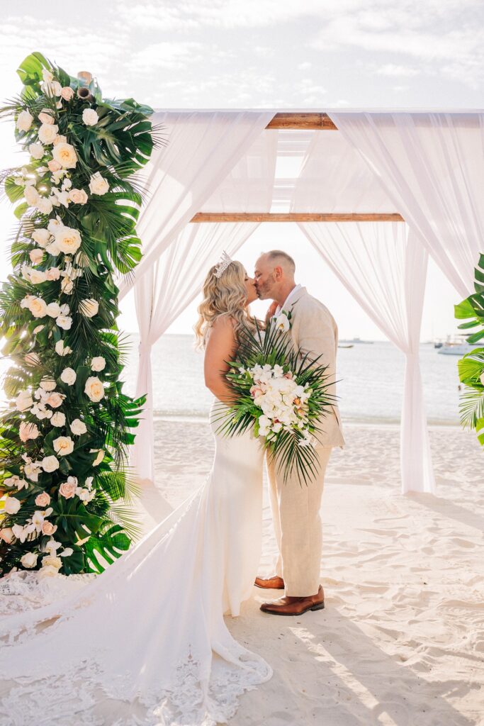 Bride and groom kissing under ceremony arch at Hyatt Regency Aruba