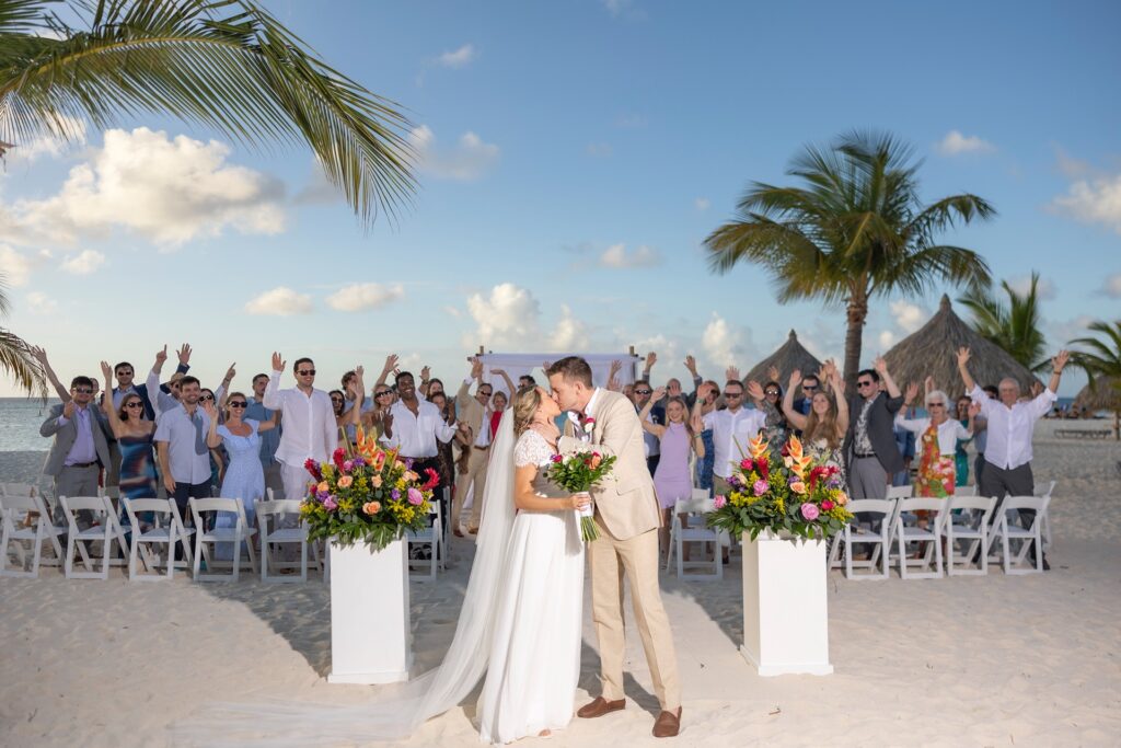 Bride and groom kissing after Aruba elopement with family behind them