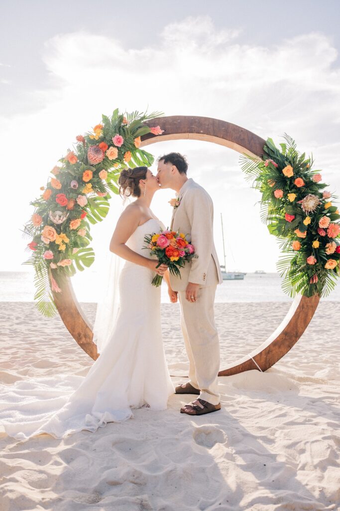 Bride and groom kissing under circle arch at Aruba wedding