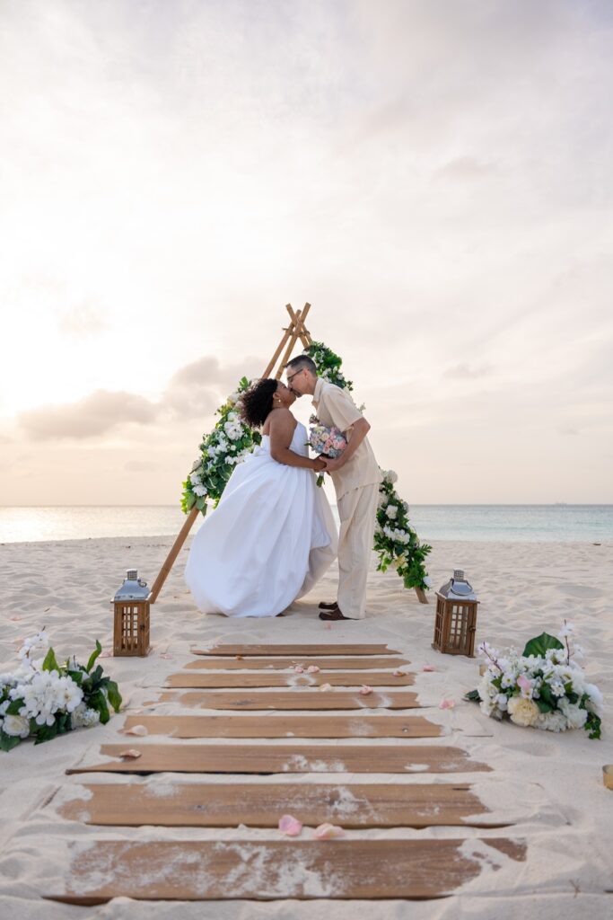 Bride and groom kissing at triangle arch Aruba wedding