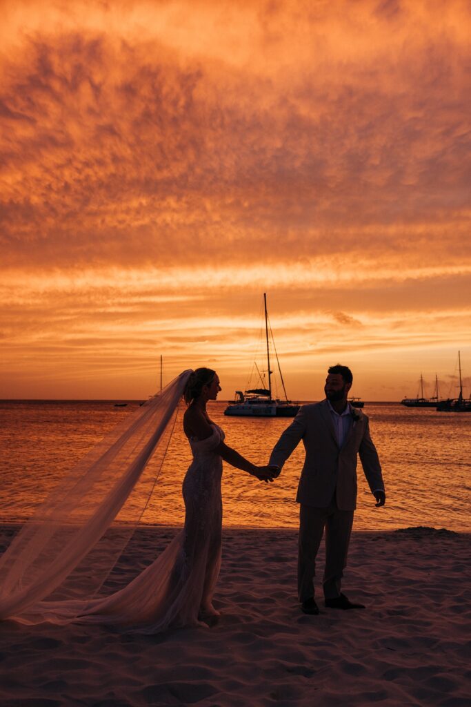 Bride and groom holding hands at Aruba sunset