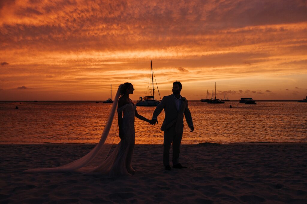 Couple walking Aruba beach at sunset after Aruba elopement