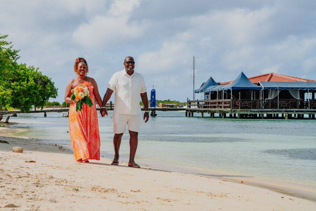 Bride and groom walking Aruba beach after ceremony
